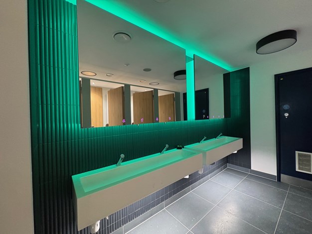 Olympia London Grand Hall washroom featuring Venesta Mirror Box units with green LED lighting