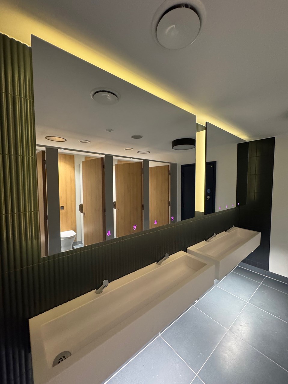 LED feature lighting yellow and etched mirror icons guiding users in Olympia washrooms